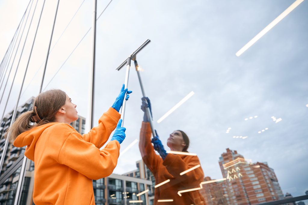 Window cleaner spraying eco-friendly solution on glass surface