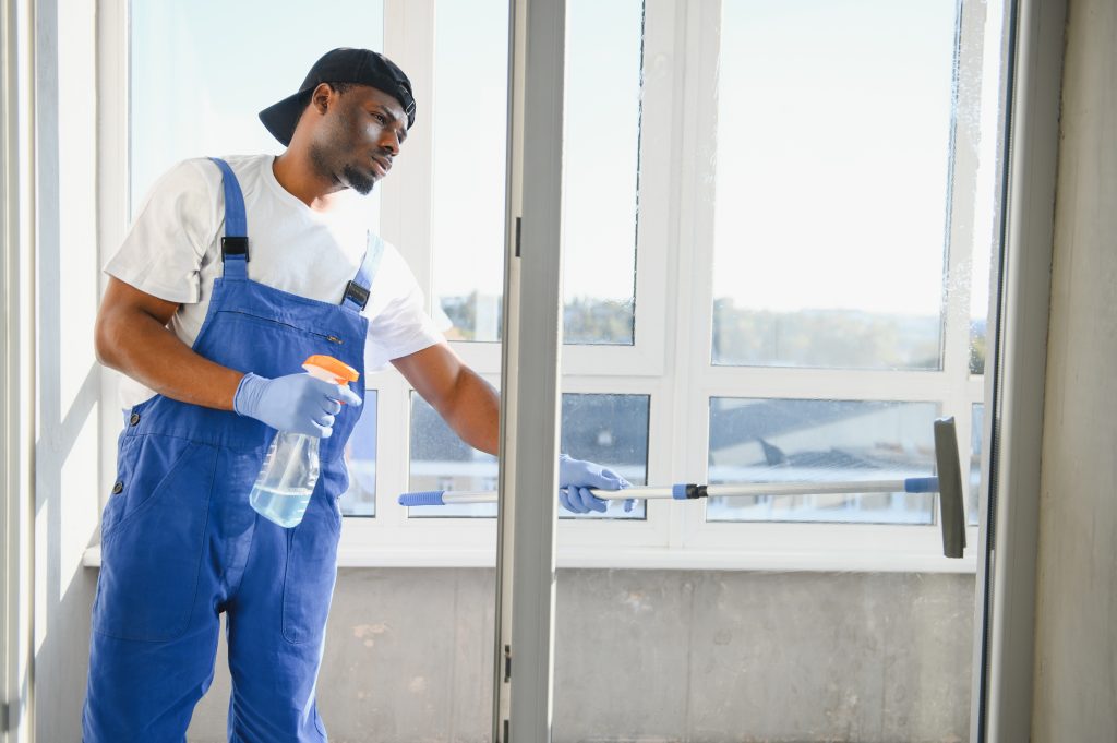 Cleaning expert wiping large glass windows in Dubai villa